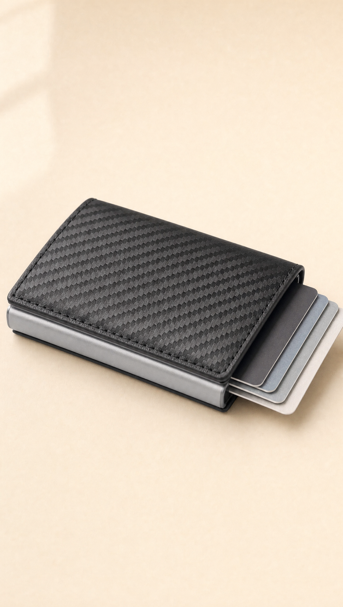 Porte-cartes Veltra Pop gris carbone avec cartes sorties, posé sur un fond crème